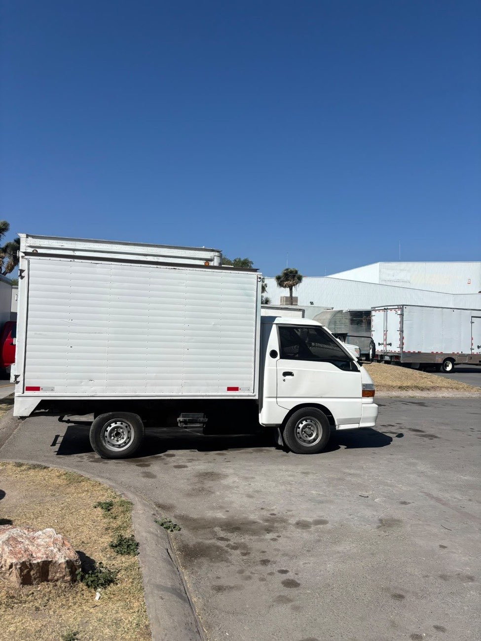 Vista lateral de una camioneta de caja blanca de RLC Express bajo cielo despejado